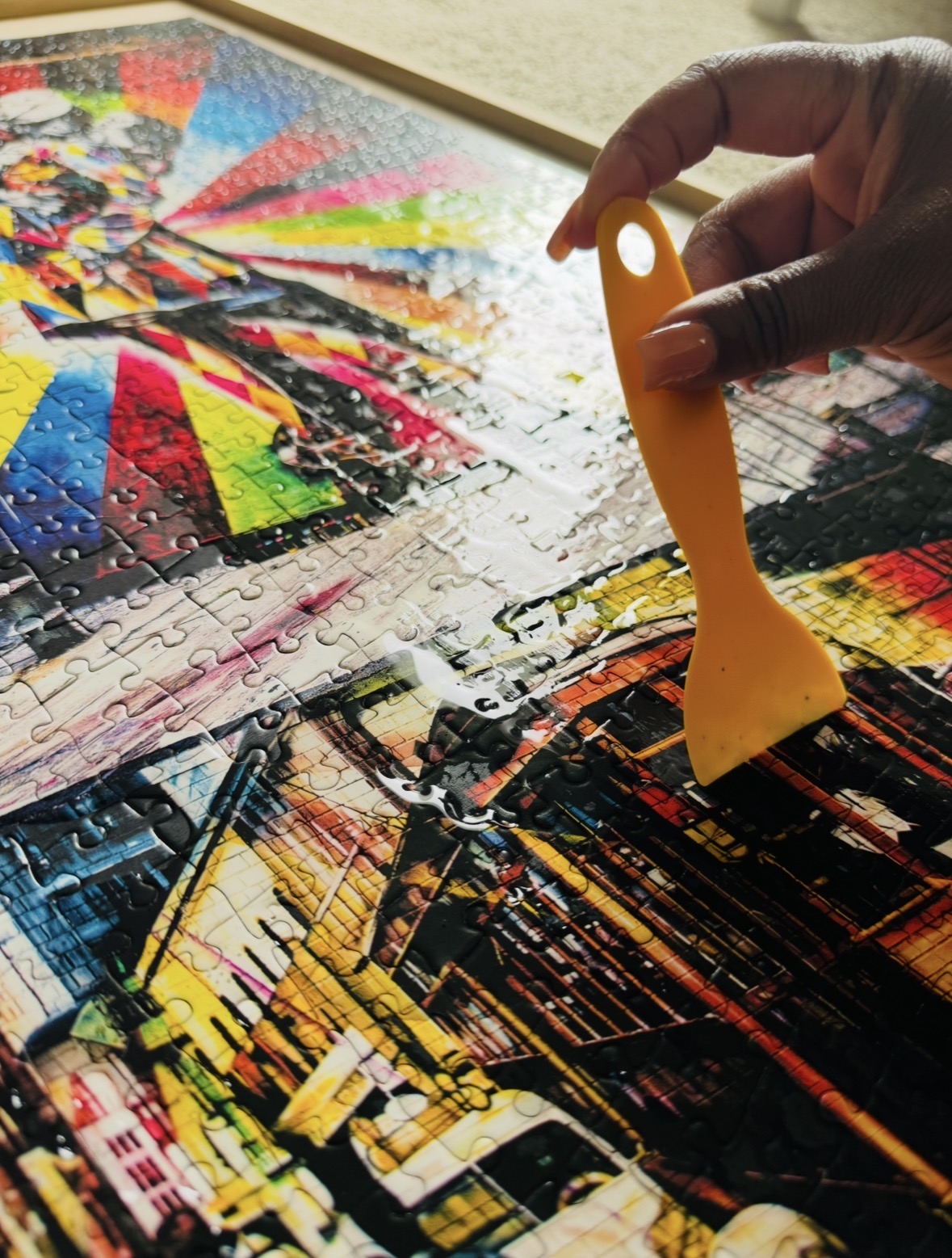 Spreading the glue evenly over the puzzle with the orange spreader.